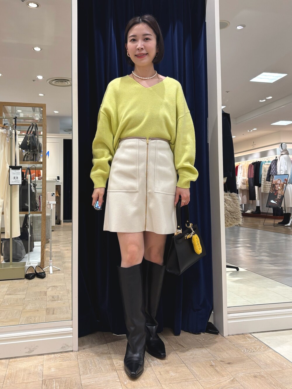 イエロー系のニット/セーター、ブラック系のブーツ、ブラック系のショルダーバッグを着用したレディースの冬コーディネートの5枚目の写真