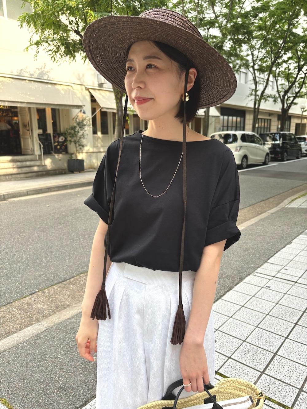 ホワイト系のその他パンツ、ブラック系のTシャツ/カットソー、ブラック系のかごバッグを着用したレディースの夏コーディネートの5枚目の写真