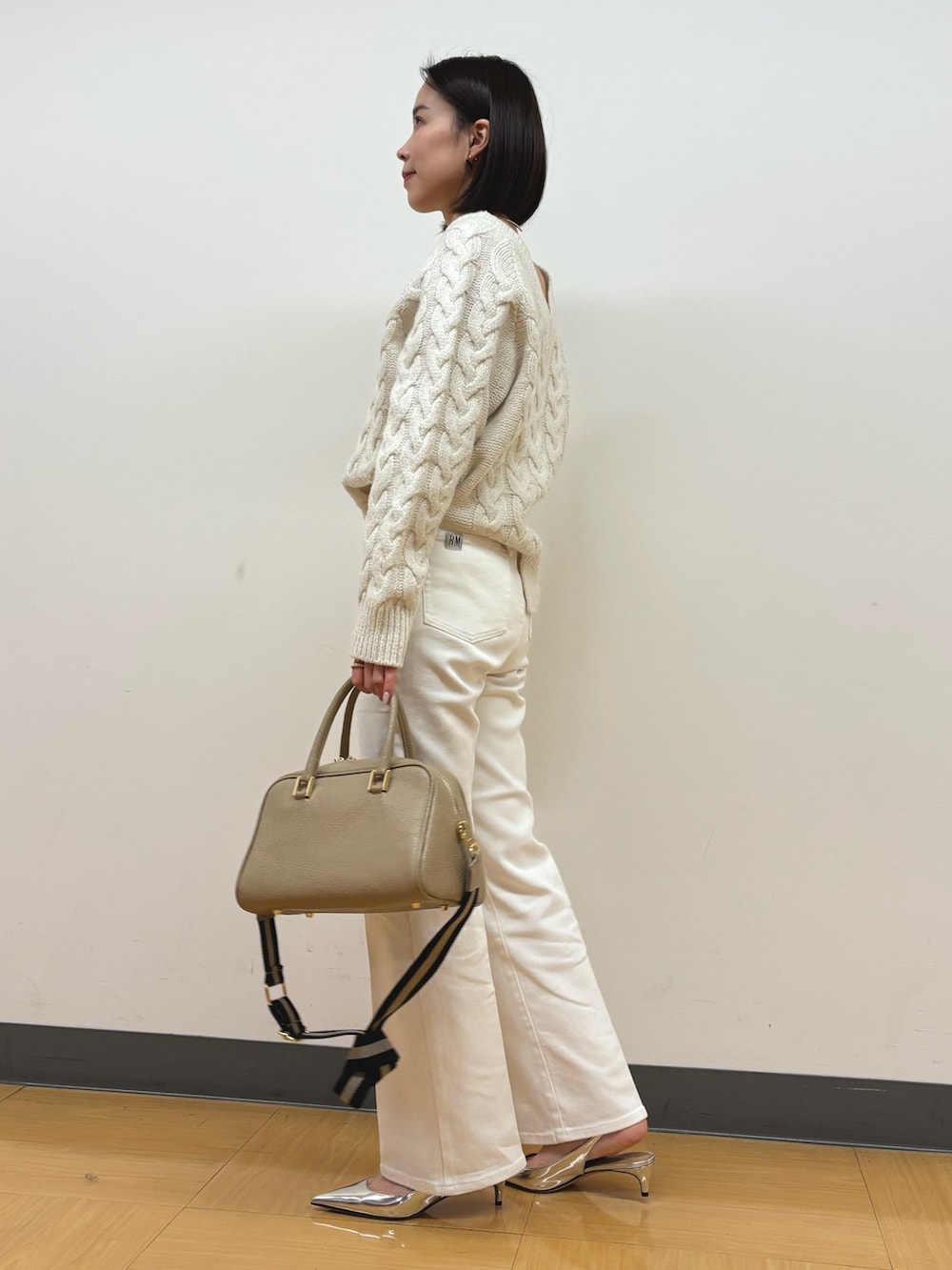 ベージュ系のショルダーバッグ、ホワイト系のデニムパンツ、ホワイト系のニット/セーターを着用したレディースの冬コーディネートの3枚目の写真