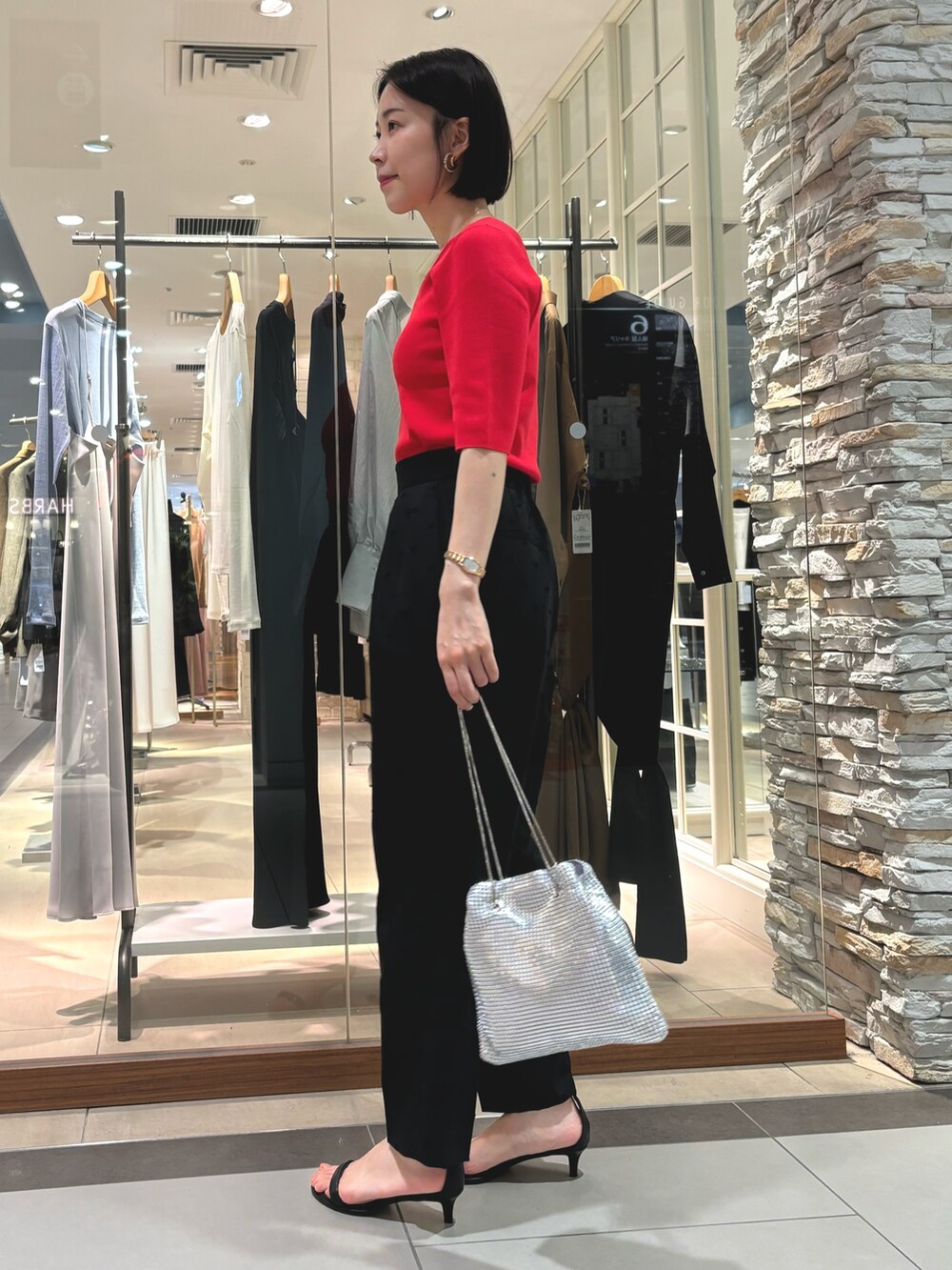 ブラック系のその他パンツ、シルバー系のショルダーバッグ、レッド系のニット/セーターを着用したレディースの夏コーディネートの3枚目の写真