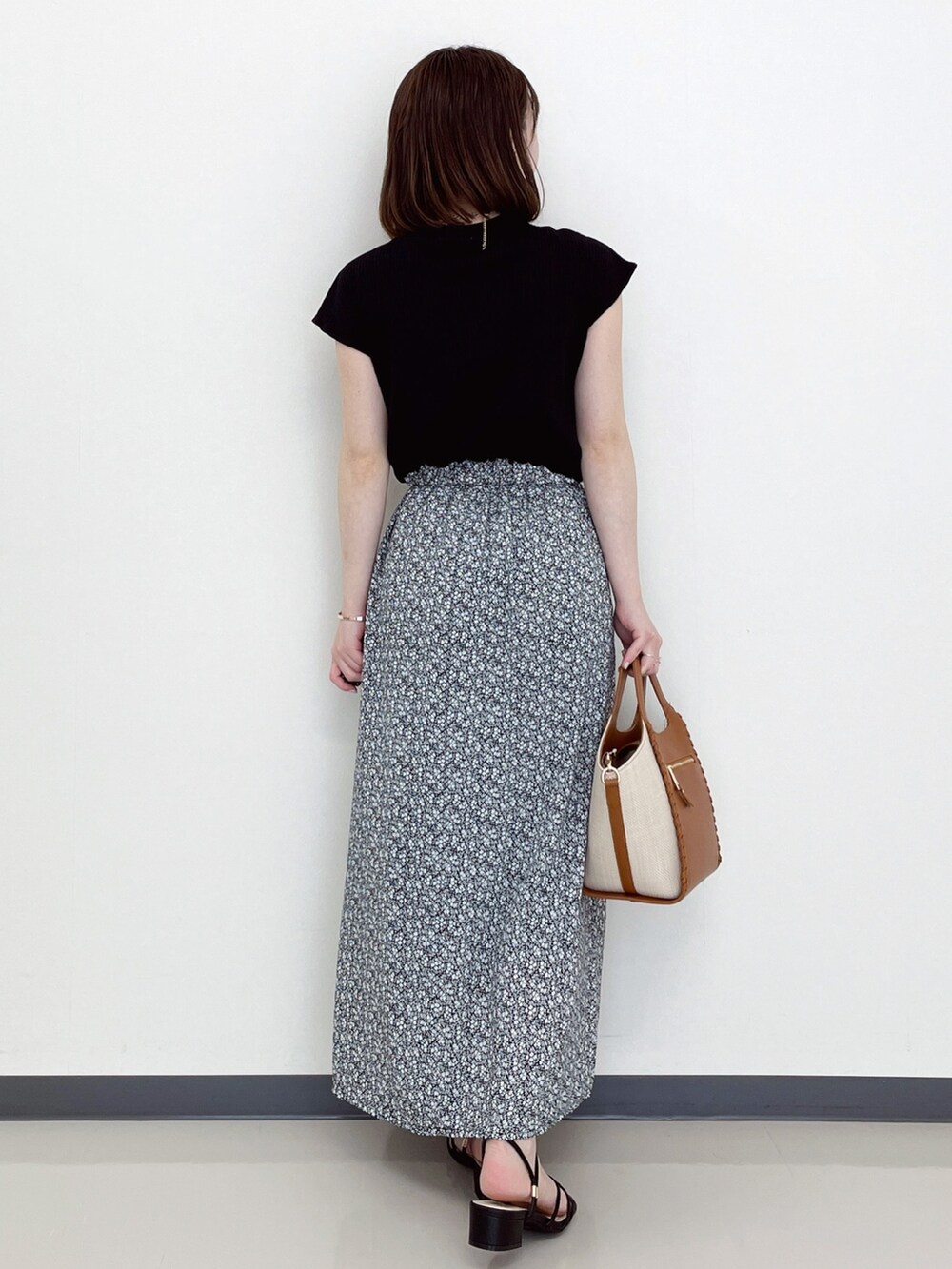 ブラック系のワンピース、ブラック系のサンダル、イエロー系のトートバッグを着用したレディースの夏コーディネートの3枚目の写真