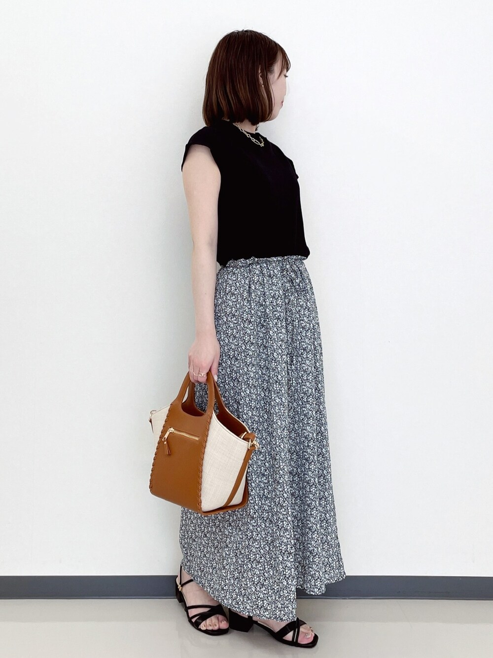 ブラック系のワンピース、ブラック系のサンダル、イエロー系のトートバッグを着用したレディースの夏コーディネートの2枚目の写真