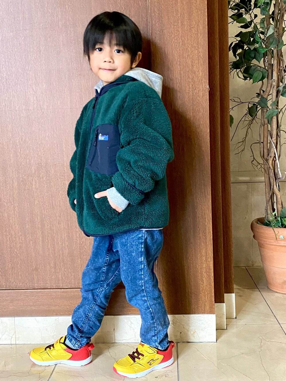 グリーン系のジャケット/アウター、ブルー系のデニムパンツ、イエロー系のスニーカーを着用したキッズの冬コーディネートの2枚目の写真