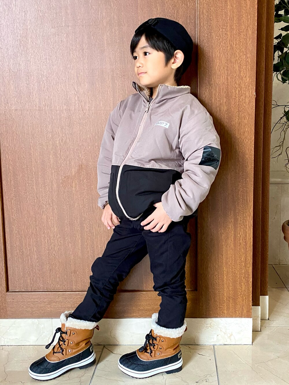 ベージュ系のジャケット/アウター、ブラック系のパンツ、ブラウン系のブーツを着用したキッズの冬コーディネートの2枚目の写真