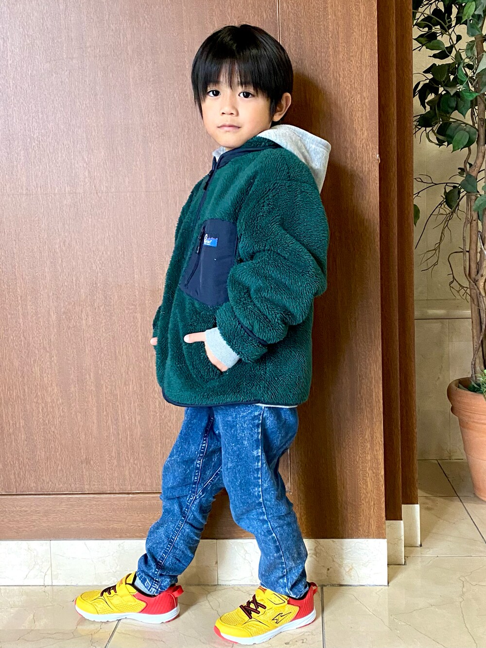 グリーン系のジャケット/アウター、ブルー系のデニムパンツ、イエロー系のスニーカーを着用したキッズの冬コーディネートの3枚目の写真