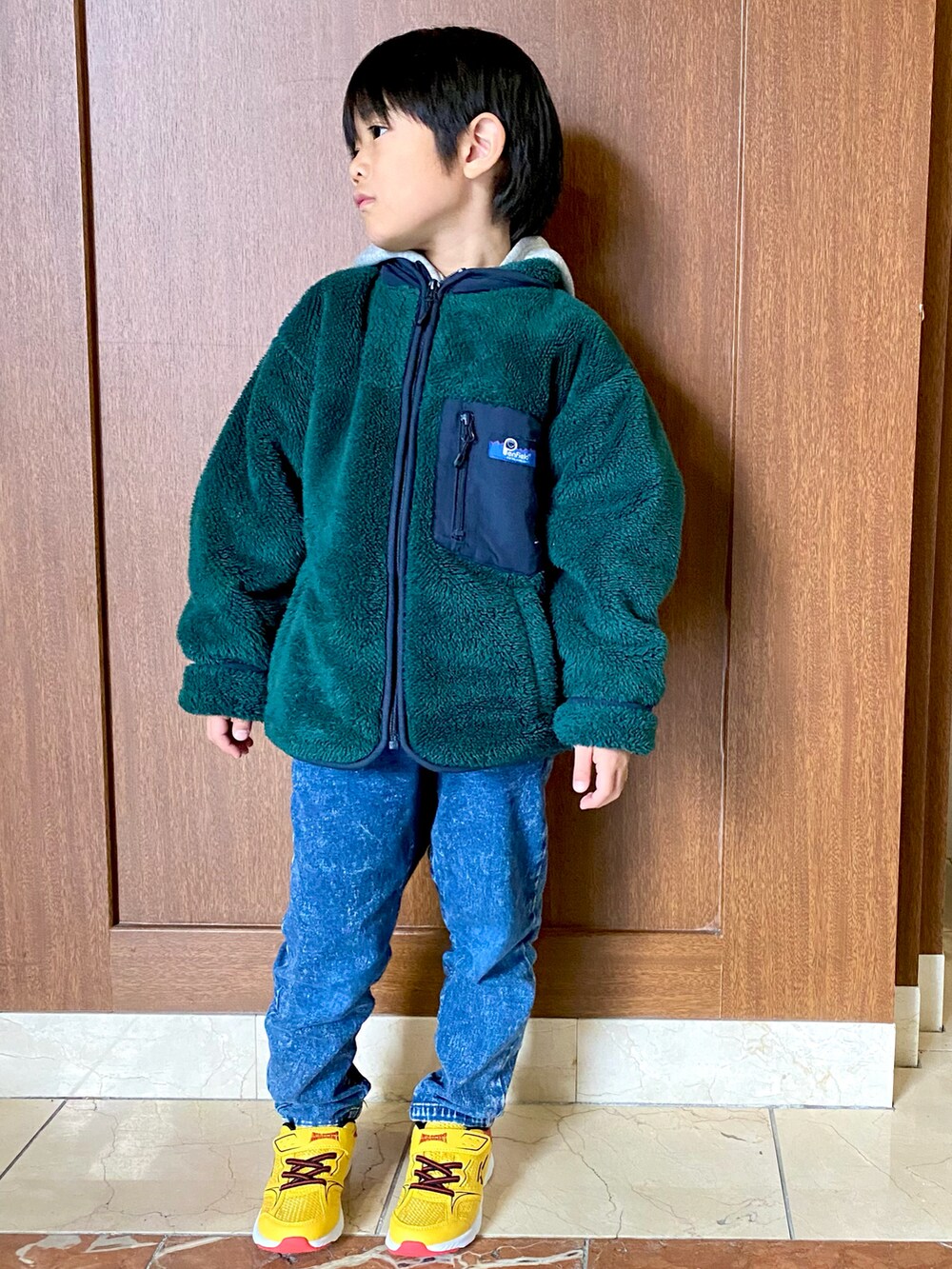 グリーン系のジャケット/アウター、ブルー系のデニムパンツ、イエロー系のスニーカーを着用したキッズの冬コーディネートの4枚目の写真