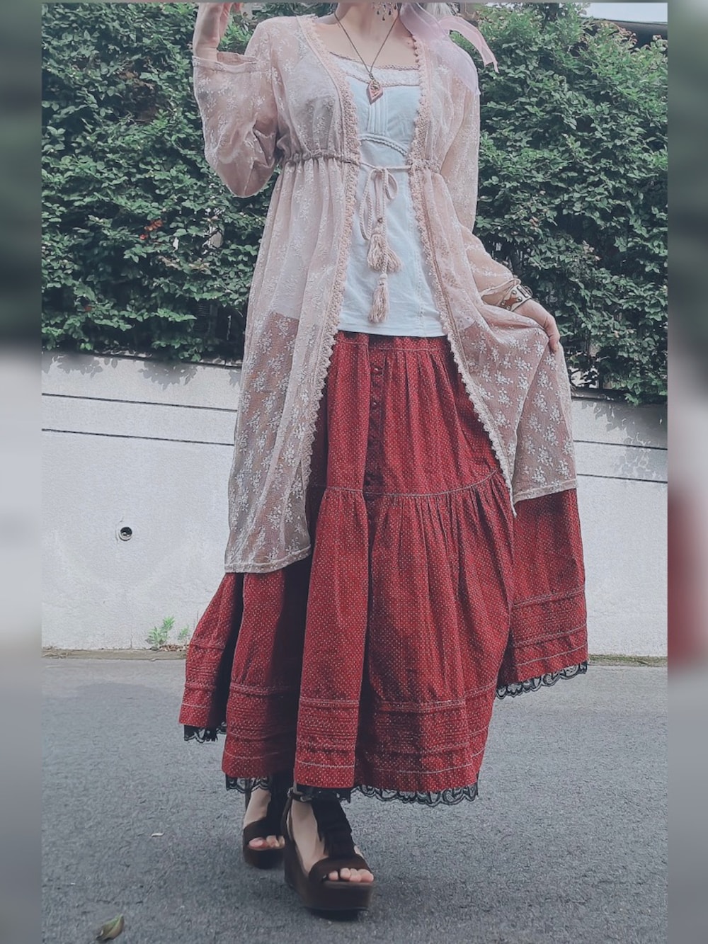 レッド系のスカート、ホワイト系のキャミソール、ピンク系のカーディガン/ボレロを着用したレディースの春コーディネートの2枚目の写真