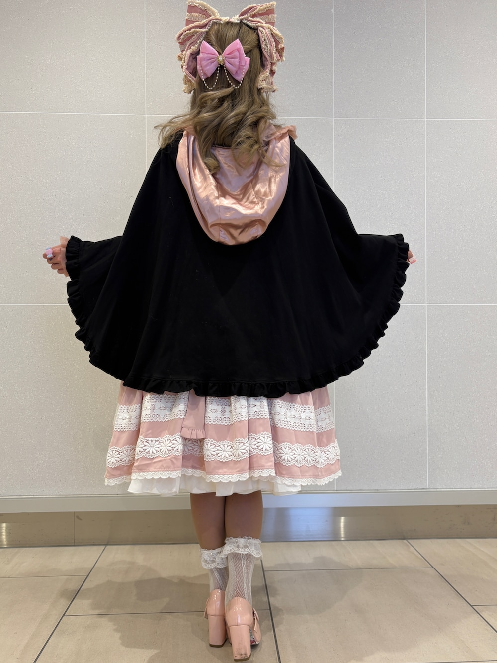 ブラック系のポンチョ、ピンク系のショルダーバッグ、ピンク系のシャツ/ブラウスを着用したレディースの秋コーディネートの2枚目の写真