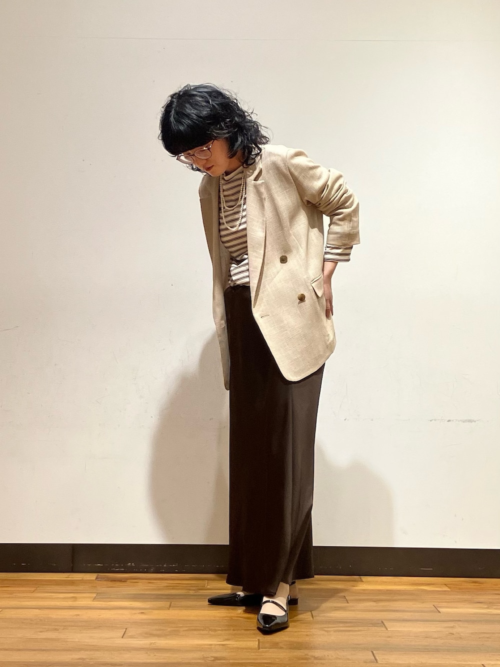 ブラウン系のスカート、ホワイト系のTシャツ/カットソー、ベージュ系のその他アウターを着用したレディースの春コーディネートの2枚目の写真