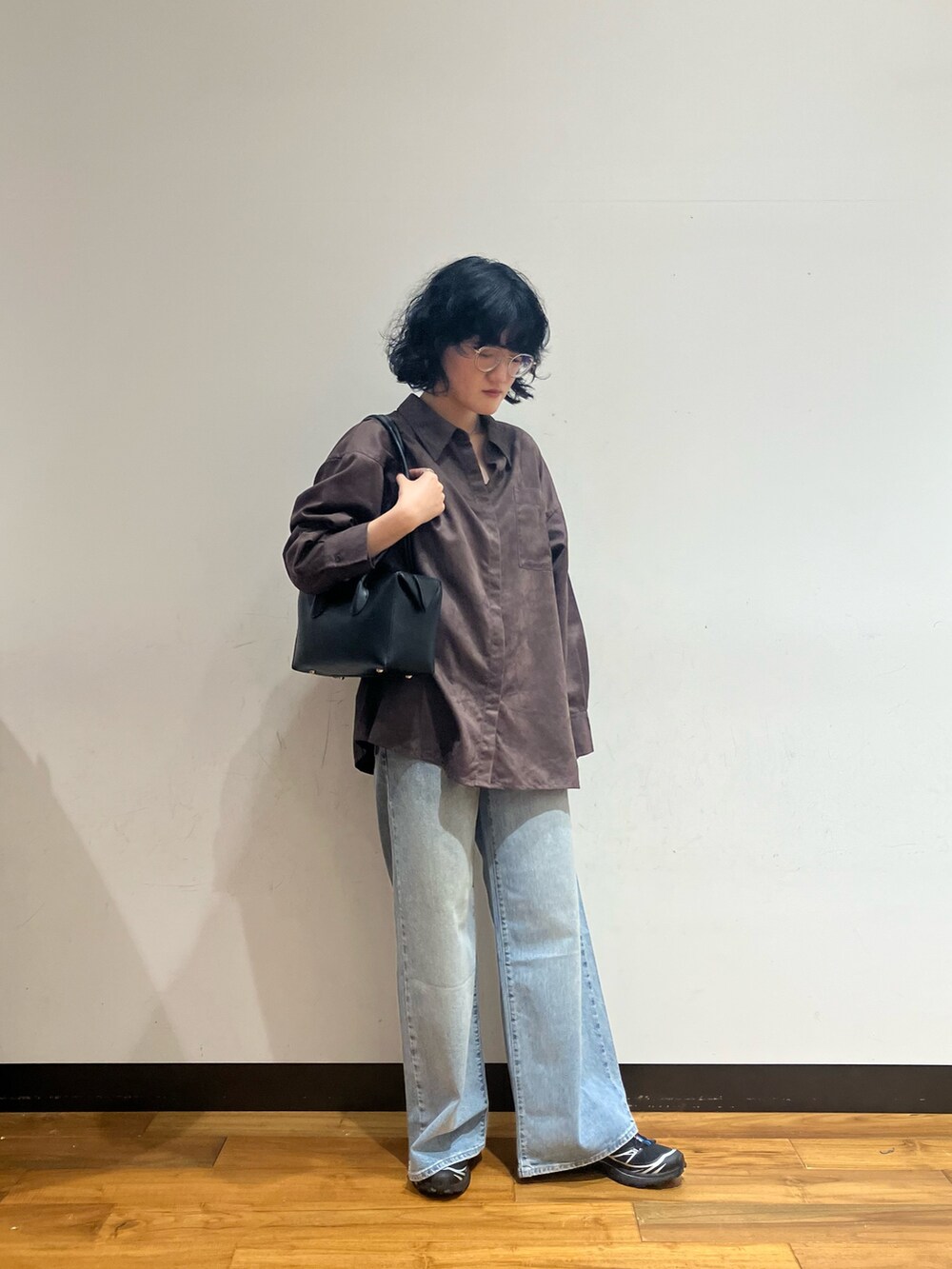 ブルー系のデニムパンツ、ブラウン系のシャツ/ブラウス、ブラック系のショルダーバッグを着用したレディースの秋コーディネートの3枚目の写真