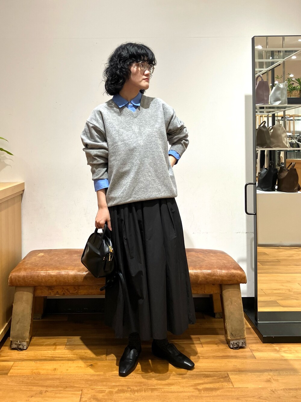 グリーン系のニット/セーター、ブルー系のシャツ/ブラウス、ブラック系のスカートを着用したレディースの秋コーディネートの3枚目の写真