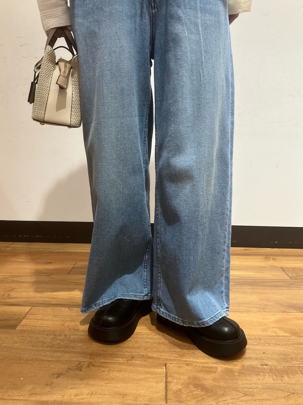 ブルー系のデニムパンツ、ベージュ系のハンドバッグ、ホワイト系のシャツ/ブラウスを着用したレディースの春コーディネートの4枚目の写真