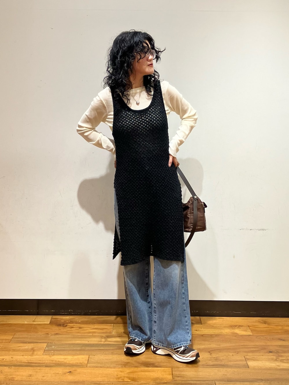 ブルー系のデニムパンツ、ブラウン系のスニーカー、ブラウン系のショルダーバッグを着用したレディースの秋コーディネートの2枚目の写真