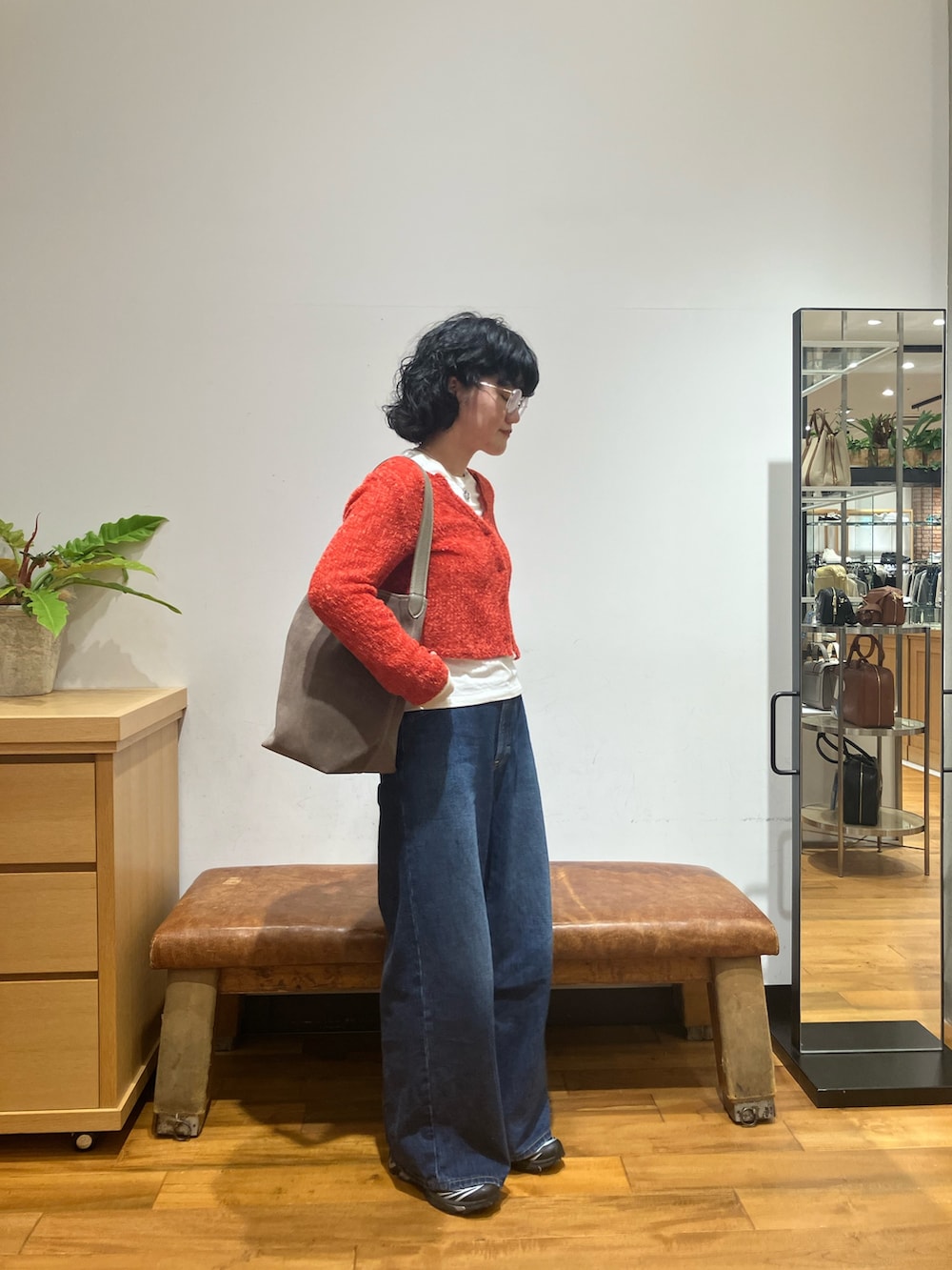 ブルー系のデニムパンツ、ブラック系のスニーカー、レッド系のカーディガン/ボレロを着用したレディースの秋コーディネートの4枚目の写真