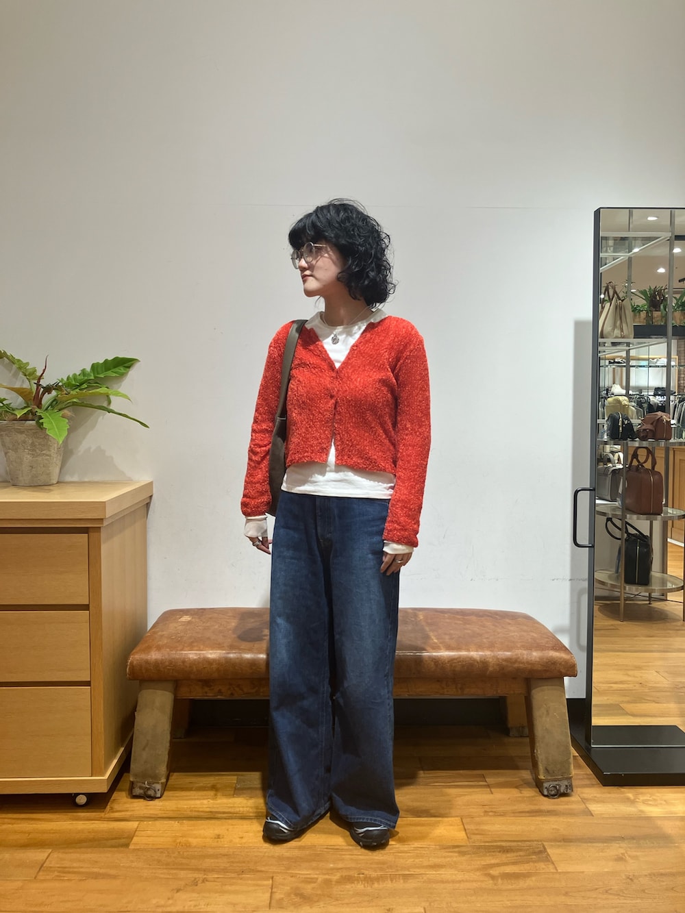 ブルー系のデニムパンツ、ブラック系のスニーカー、レッド系のカーディガン/ボレロを着用したレディースの秋コーディネートの3枚目の写真