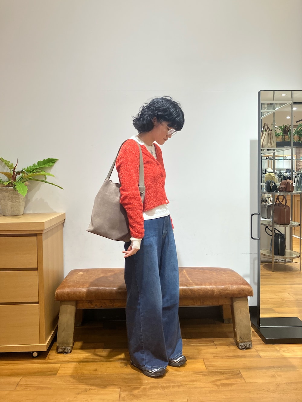 ブルー系のデニムパンツ、ブラック系のスニーカー、レッド系のカーディガン/ボレロを着用したレディースの秋コーディネートの2枚目の写真