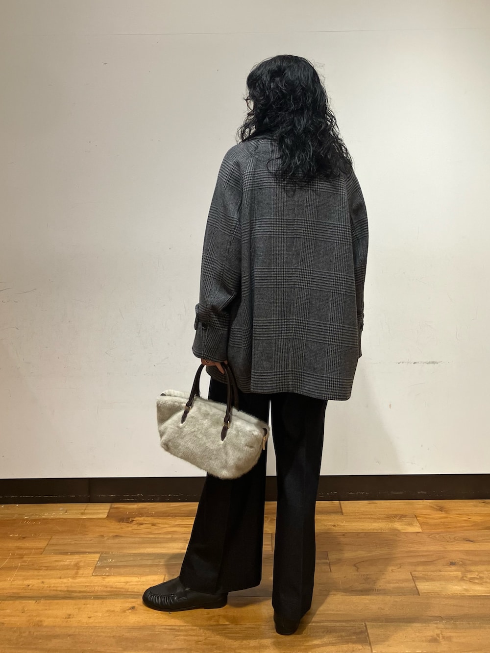 グレー系のピーコート、ブルー系のデニムパンツ、グレー系のハンドバッグを着用したレディースの秋コーディネートの4枚目の写真