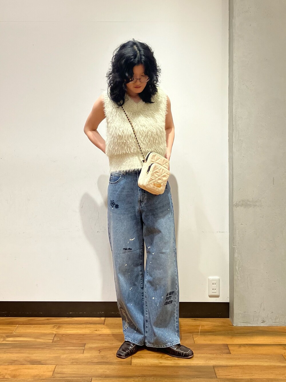 ホワイト系のベスト、ブルー系のデニムパンツ、ホワイト系のショルダーバッグを着用したレディースの夏コーディネートの2枚目の写真