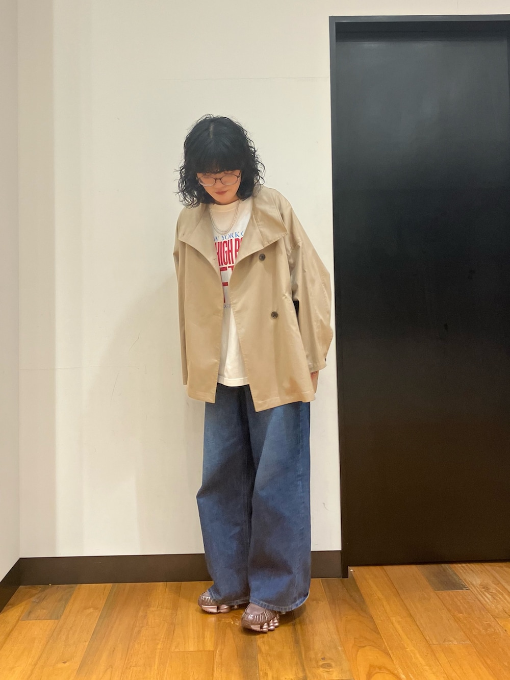 ホワイト系のTシャツ/カットソー、ベージュ系のトレンチコート、ブルー系のデニムパンツを着用したレディースの冬コーディネートの3枚目の写真