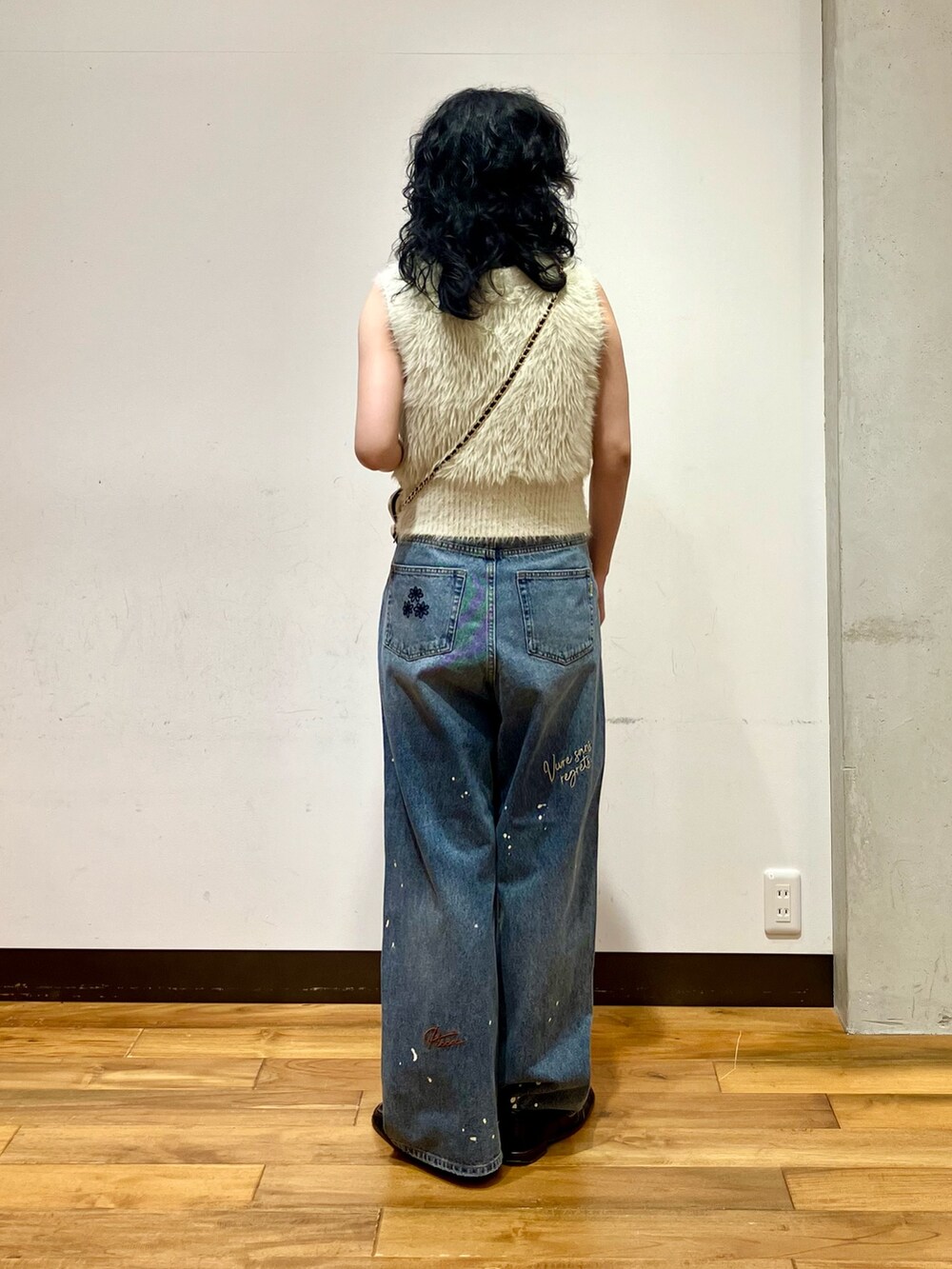 ホワイト系のベスト、ブルー系のデニムパンツ、ホワイト系のショルダーバッグを着用したレディースの夏コーディネートの4枚目の写真