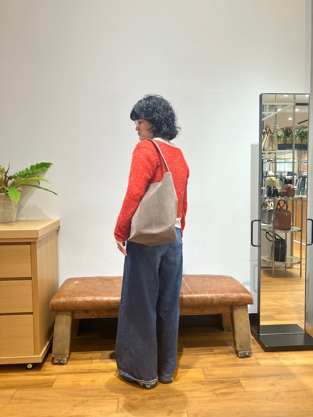 ブルー系のデニムパンツ、ブラック系のスニーカー、レッド系のカーディガン/ボレロを着用したレディースの秋コーディネートの5枚目の写真