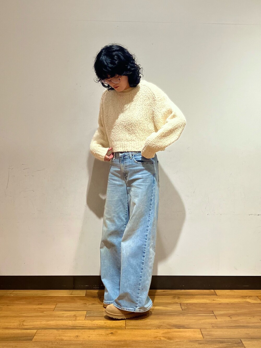 ブルー系のデニムパンツ、ブラウン系のショルダーバッグ、ホワイト系のムートンコートを着用したレディースの冬コーディネートの4枚目の写真