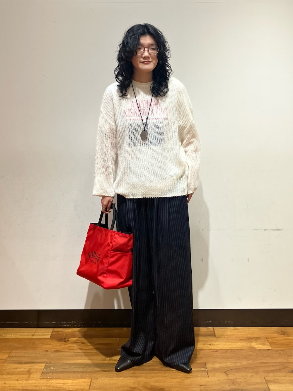 ホワイト系のニット/セーター、レッド系のトートバッグ、ホワイト系のTシャツ/カットソーを着用したレディースの秋コーディネートの4枚目の写真