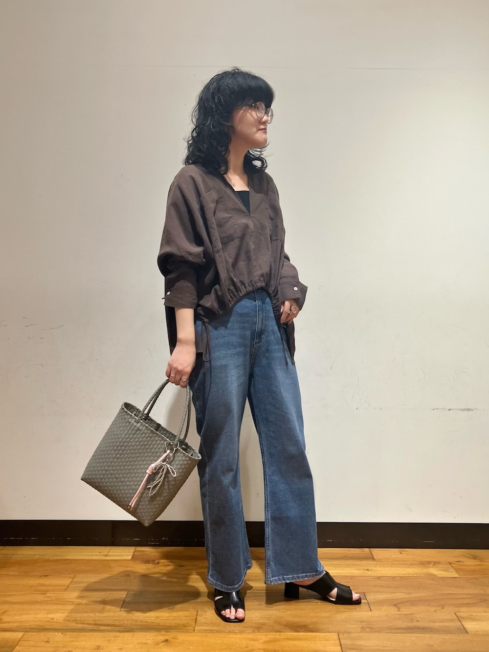 ブラック系のタンクトップ、ブルー系のデニムパンツ、ブラウン系のシャツ/ブラウスを着用したレディースの春コーディネートの3枚目の写真