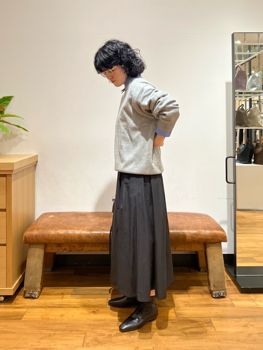 グリーン系のニット/セーター、ブルー系のシャツ/ブラウス、ブラック系のスカートを着用したレディースの秋コーディネートの2枚目の写真