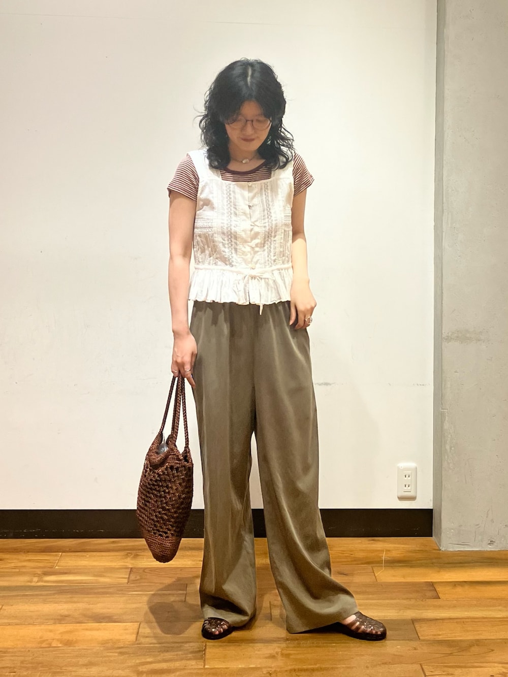 ブラウン系のトートバッグ、ホワイト系のシャツ/ブラウス、ブラウン系のTシャツ/カットソーを着用したレディースの夏コーディネートの3枚目の写真