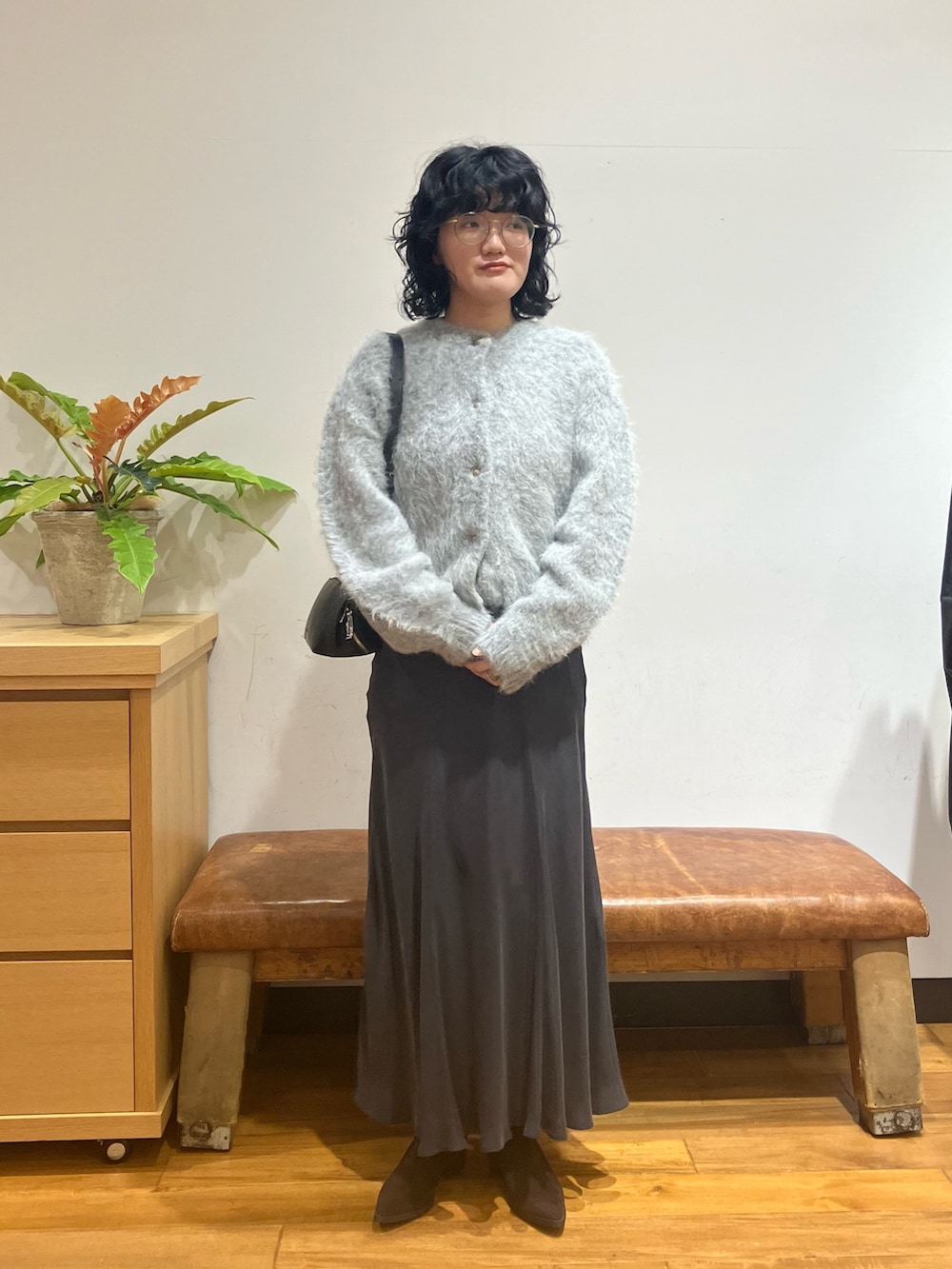 グレー系のスカート、グレー系のカーディガン/ボレロ、ブラック系のショルダーバッグを着用したレディースの秋コーディネートの2枚目の写真