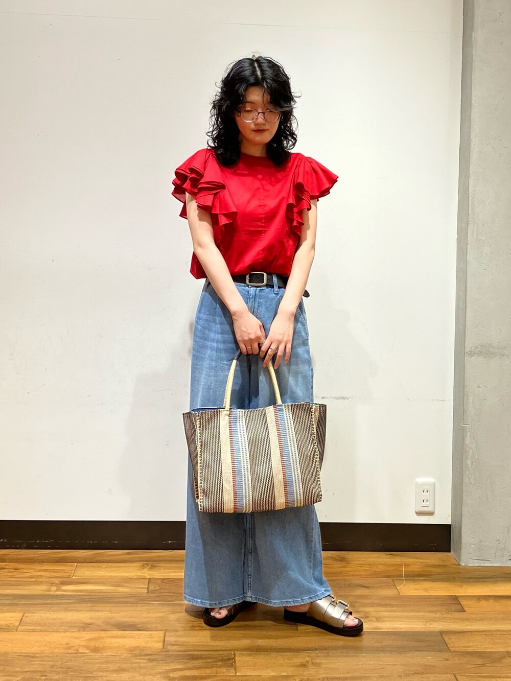 ブルー系のデニムパンツ、レッド系のシャツ/ブラウス、シルバー系のサンダルを着用したレディースの夏コーディネートの2枚目の写真