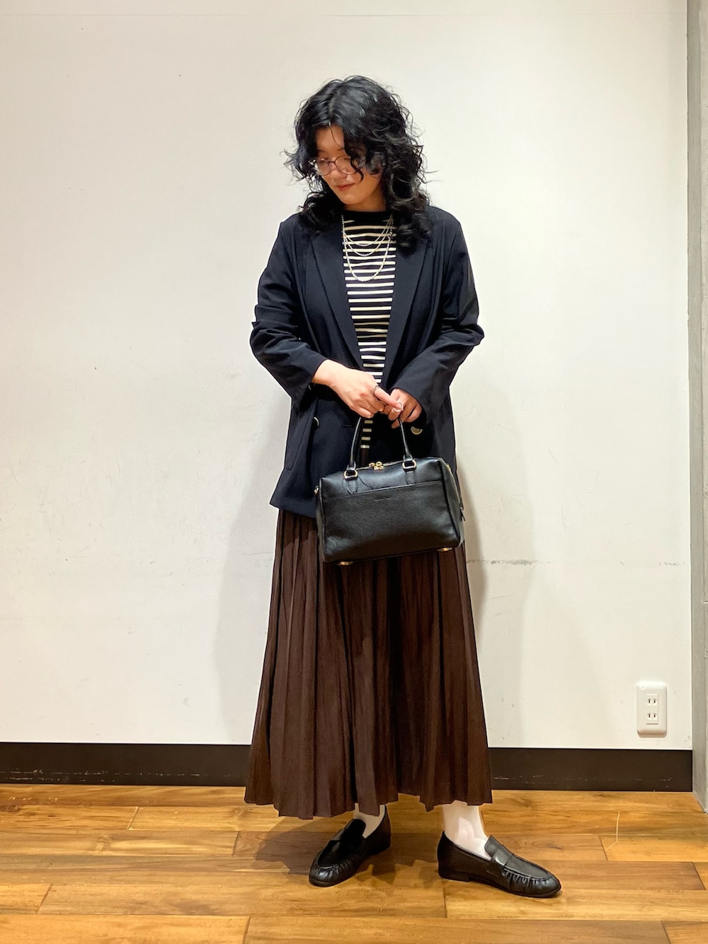 ブラウン系のスカート、ブラック系のローファー、ブラック系のTシャツ/カットソーを着用したレディースの秋コーディネートの3枚目の写真