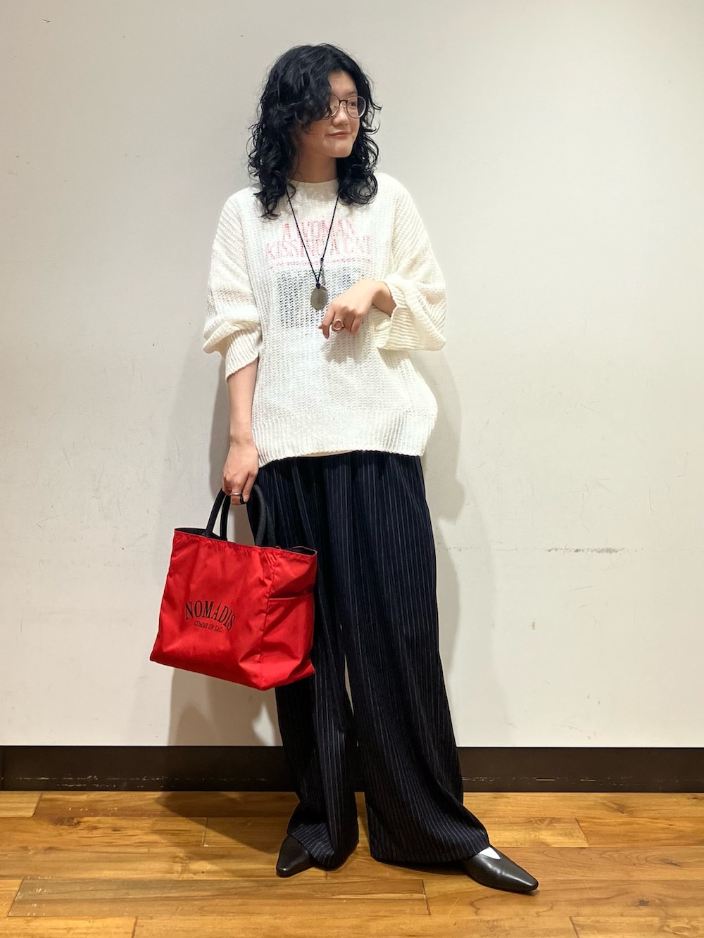ホワイト系のニット/セーター、レッド系のトートバッグ、ホワイト系のTシャツ/カットソーを着用したレディースの秋コーディネートの3枚目の写真
