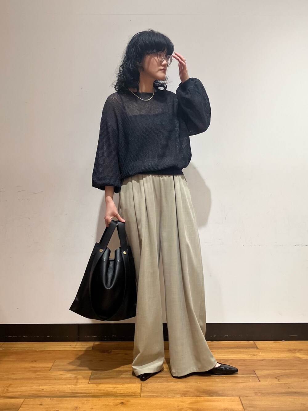 ベージュ系のその他パンツ、グレー系のニット/セーター、ブラック系のトートバッグを着用したレディースの春コーディネートの2枚目の写真