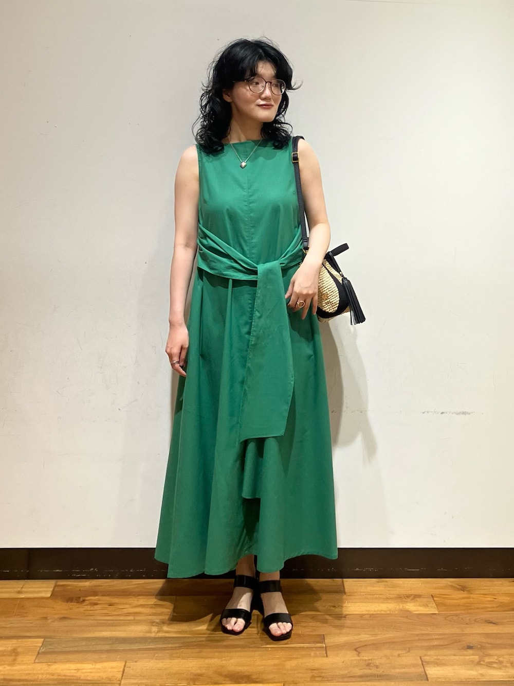 ベージュ系のかごバッグ、グリーン系のワンピース、ブラック系のサンダルを着用したレディースの夏コーディネートの2枚目の写真