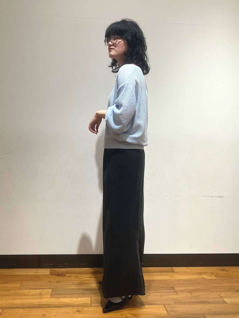 ブルー系のニット/セーター、ブラック系のスカートを着用したレディースの春コーディネートの2枚目の写真