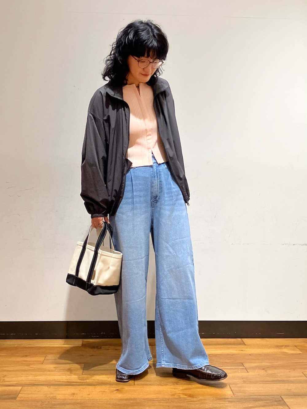 ブラック系のトートバッグ、ブルー系のデニムパンツ、グレー系のブルゾンを着用したレディースの春コーディネートの3枚目の写真