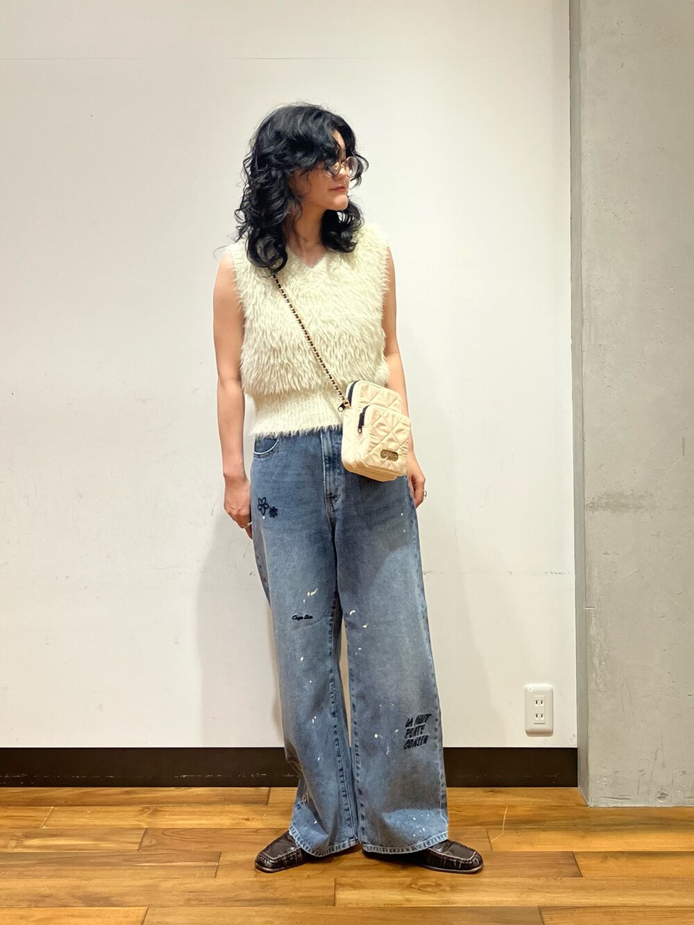 ホワイト系のベスト、ブルー系のデニムパンツ、ホワイト系のショルダーバッグを着用したレディースの夏コーディネートの3枚目の写真