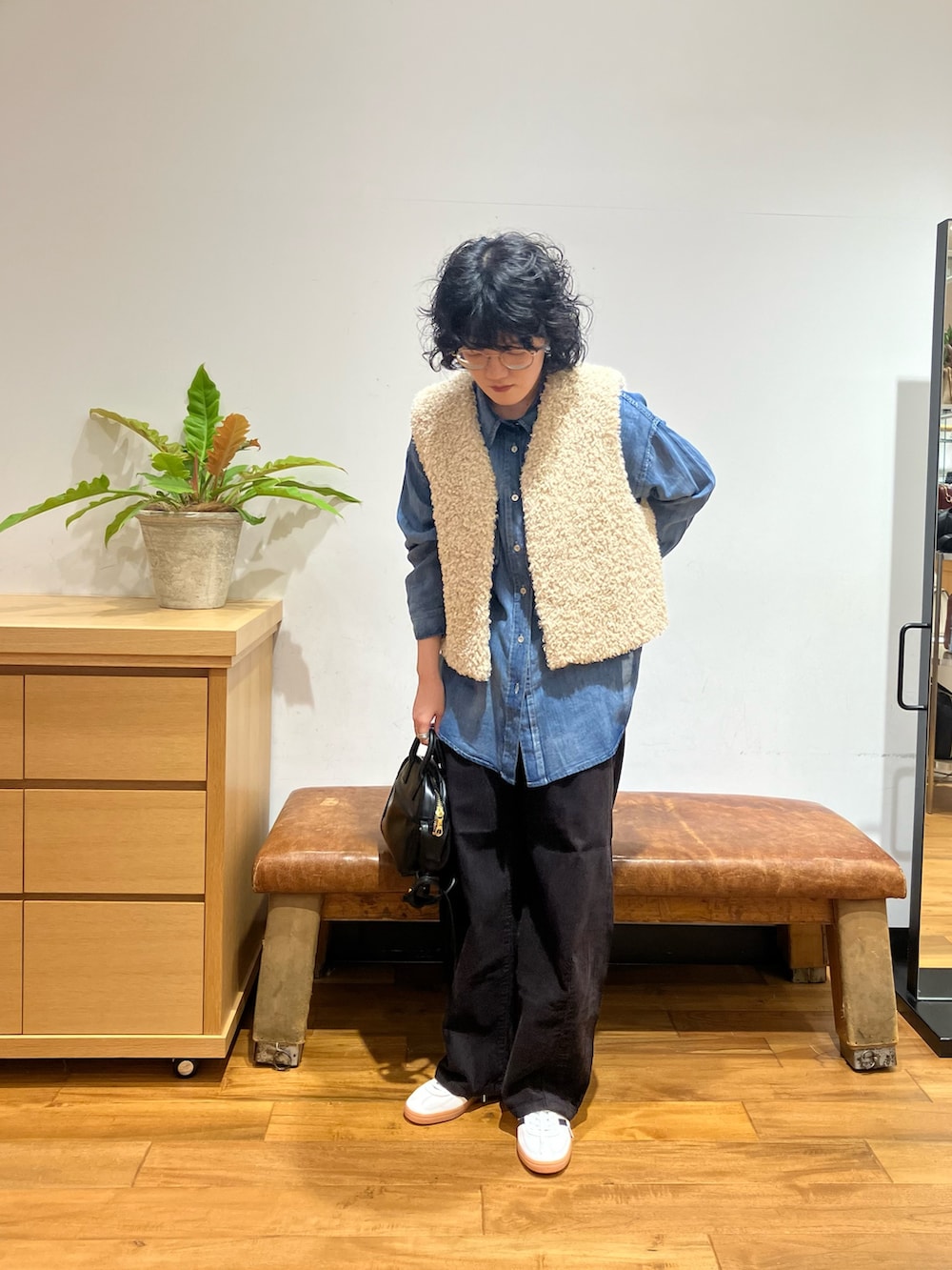 ホワイト系のベスト、グレー系のその他パンツ、ブラック系のショルダーバッグを着用したレディースの秋コーディネートの2枚目の写真