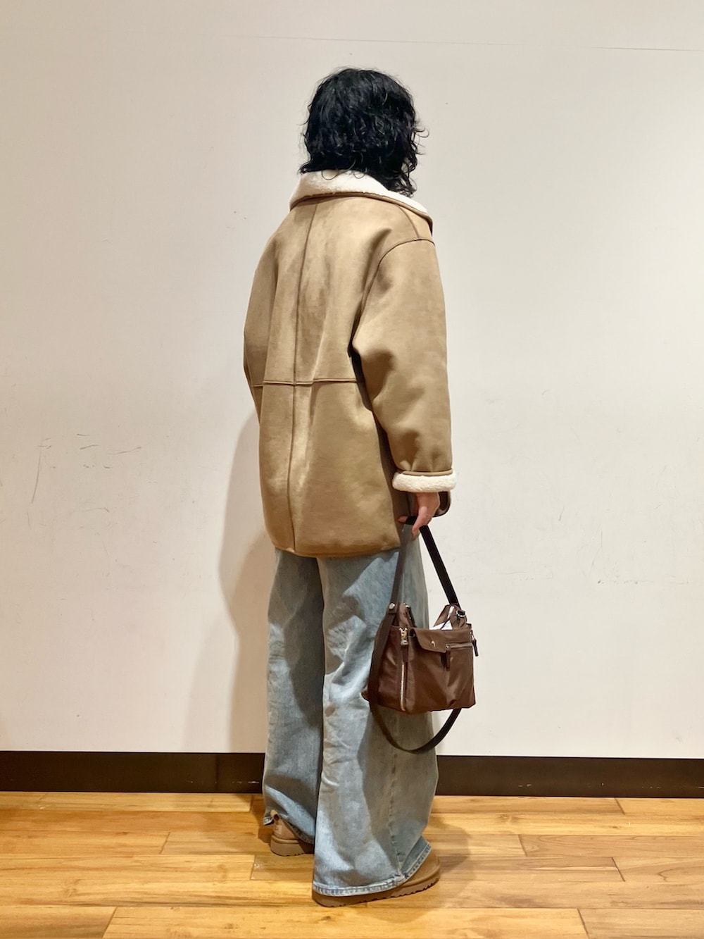 ブルー系のデニムパンツ、ブラウン系のショルダーバッグ、ホワイト系のムートンコートを着用したレディースの冬コーディネートの3枚目の写真