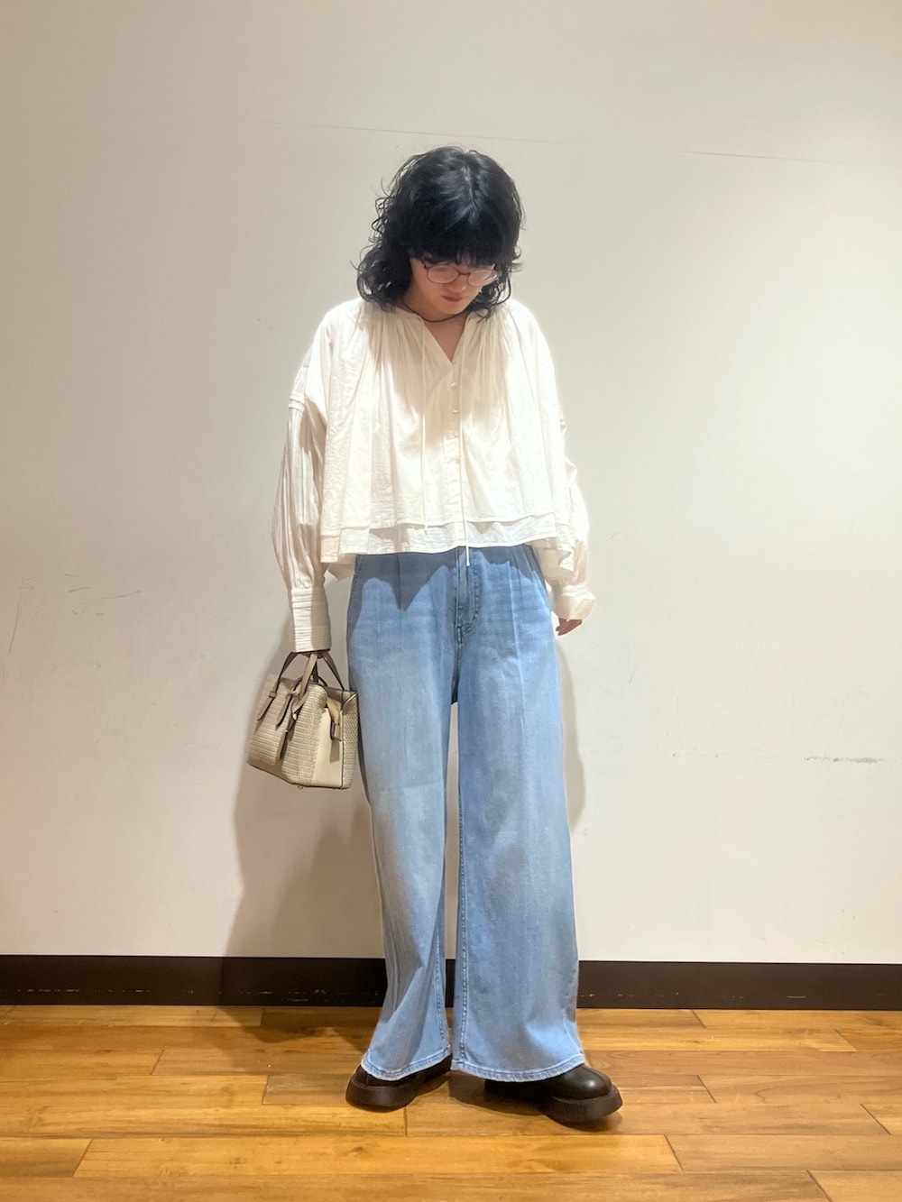 ブルー系のデニムパンツ、ベージュ系のハンドバッグ、ホワイト系のシャツ/ブラウスを着用したレディースの春コーディネートの3枚目の写真