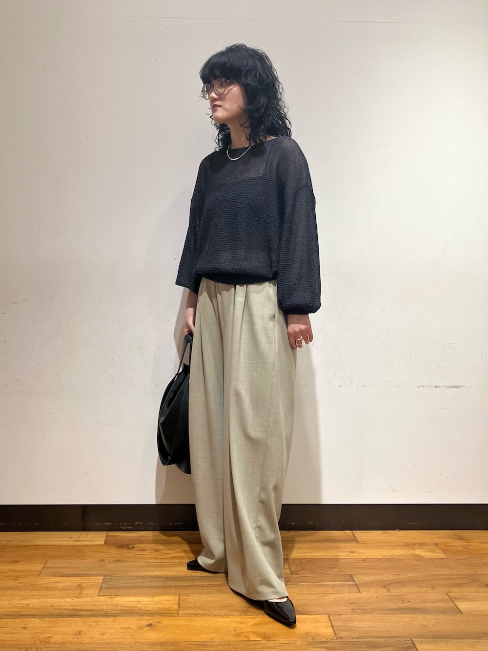 ベージュ系のその他パンツ、グレー系のニット/セーター、ブラック系のトートバッグを着用したレディースの春コーディネートの3枚目の写真
