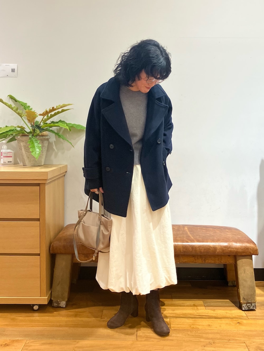 ブルー系のピーコート、ホワイト系のスカート、ベージュ系のショルダーバッグを着用したレディースの秋コーディネートの2枚目の写真