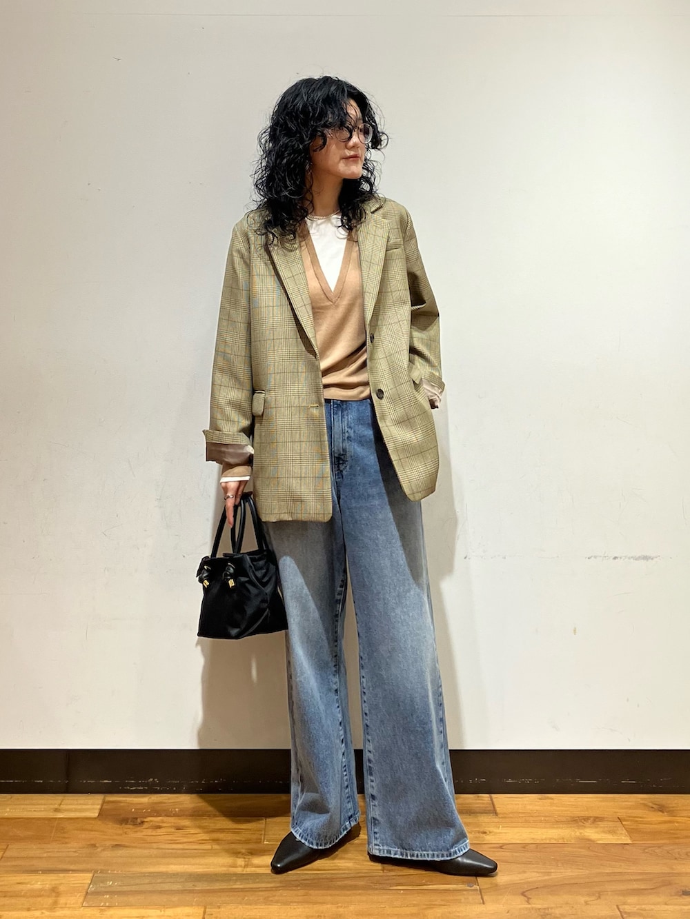 ブラック系のその他シューズ、ブルー系のデニムパンツ、ベージュ系のニット/セーターを着用したレディースの秋コーディネートの2枚目の写真