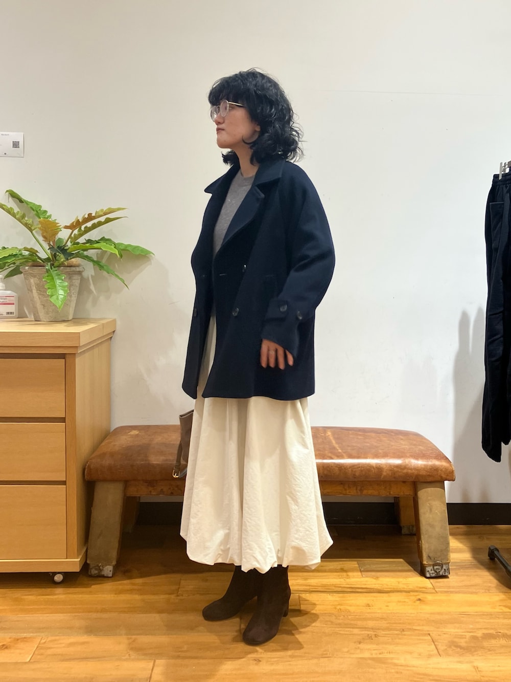 ブルー系のピーコート、ホワイト系のスカート、ベージュ系のショルダーバッグを着用したレディースの秋コーディネートの3枚目の写真