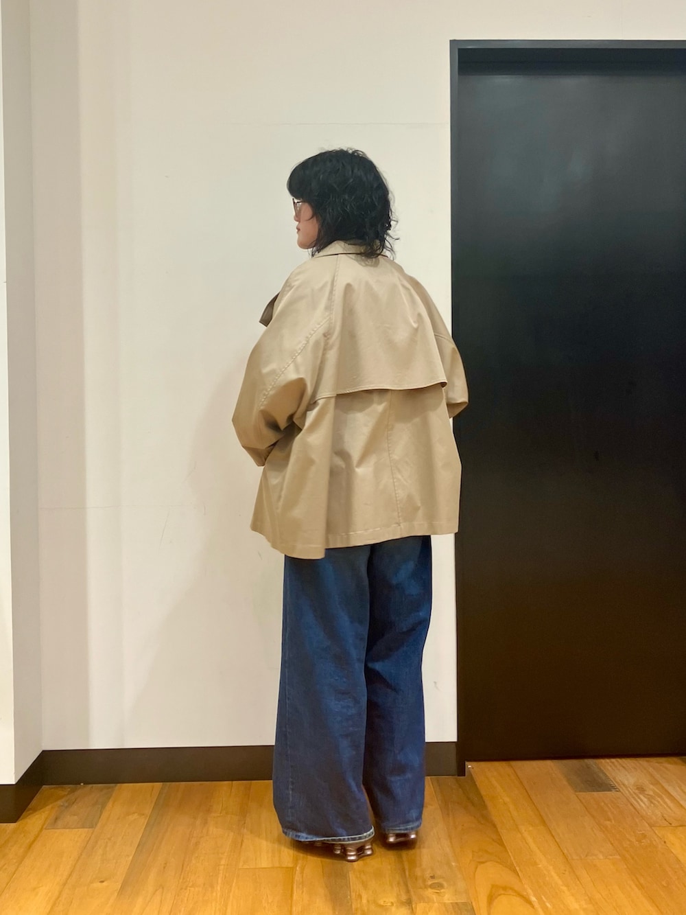 ホワイト系のTシャツ/カットソー、ベージュ系のトレンチコート、ブルー系のデニムパンツを着用したレディースの冬コーディネートの2枚目の写真