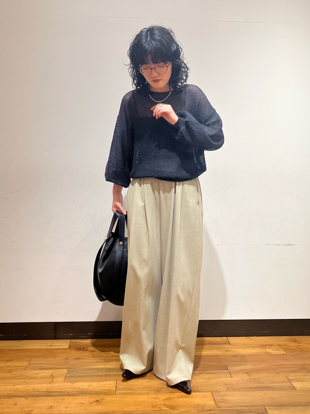 ベージュ系のその他パンツ、グレー系のニット/セーター、ブラック系のトートバッグを着用したレディースの春コーディネートの4枚目の写真