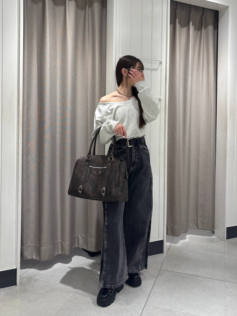 ベージュ系のスウェット、ブラック系のデニムパンツ、ブラウン系のボストンバッグを着用したレディースの冬コーディネートの2枚目の写真