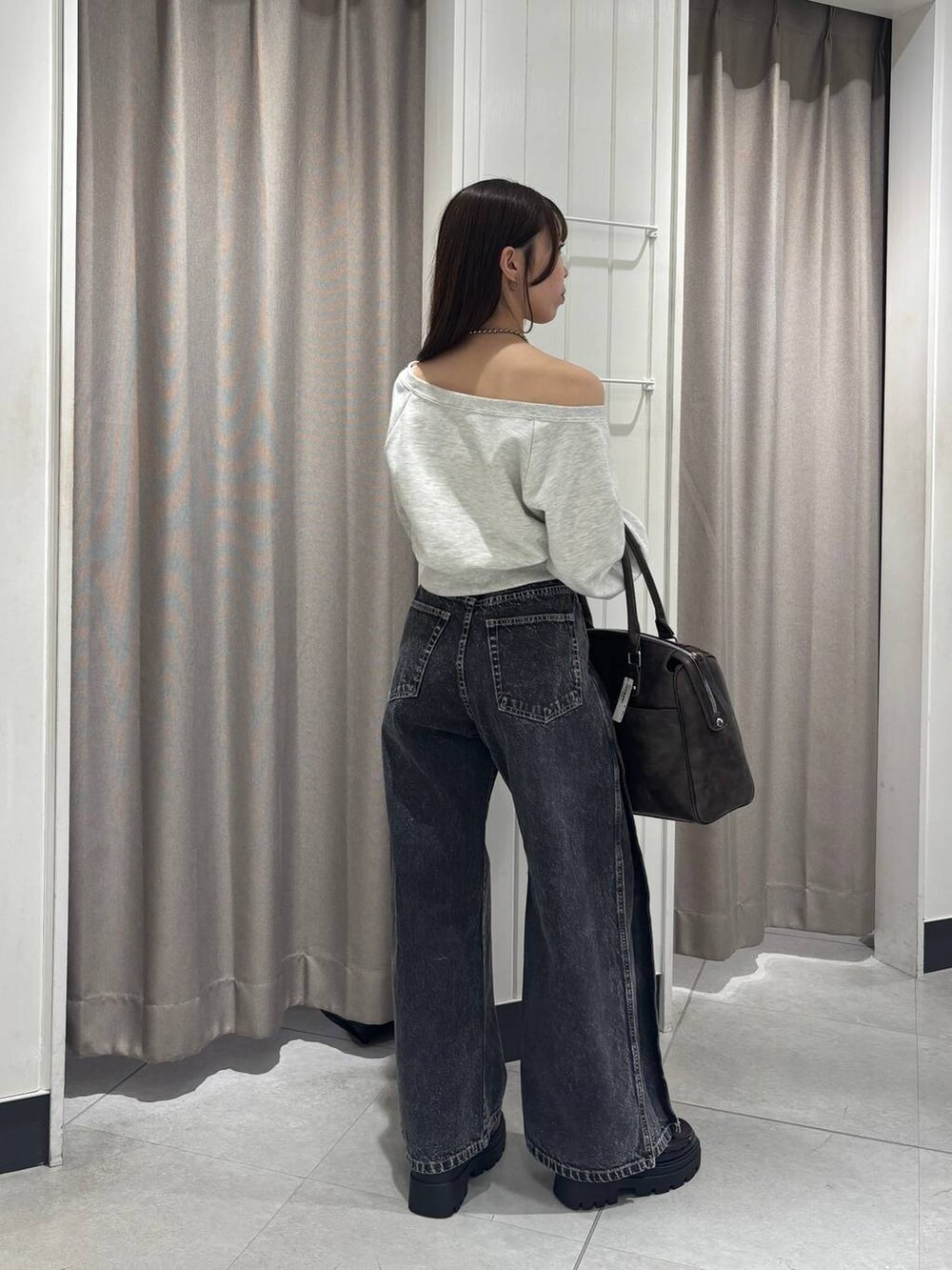 ベージュ系のスウェット、ブラック系のデニムパンツ、ブラウン系のボストンバッグを着用したレディースの冬コーディネートの4枚目の写真